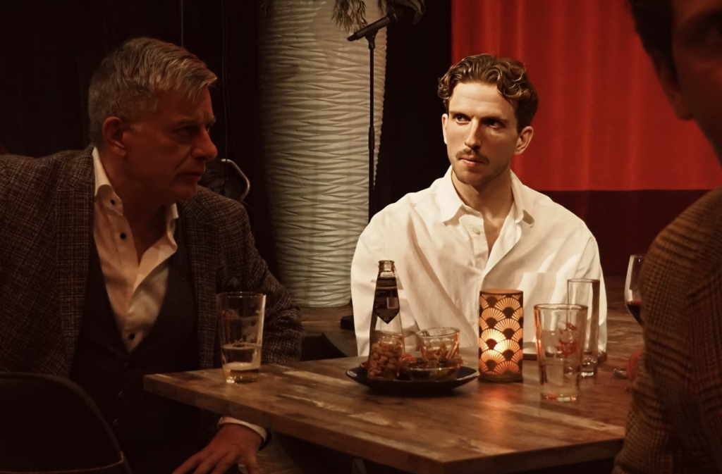 Jelle van der Heyden in gesprek aan tafel tijdens een bijeenkomst, luisterend met aandacht in een informele setting.